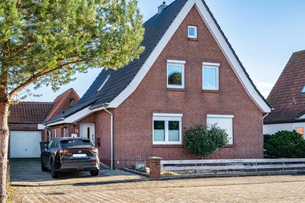 a red brick house with a car parked in front at Ferienwohnung Anne in Bremervörde