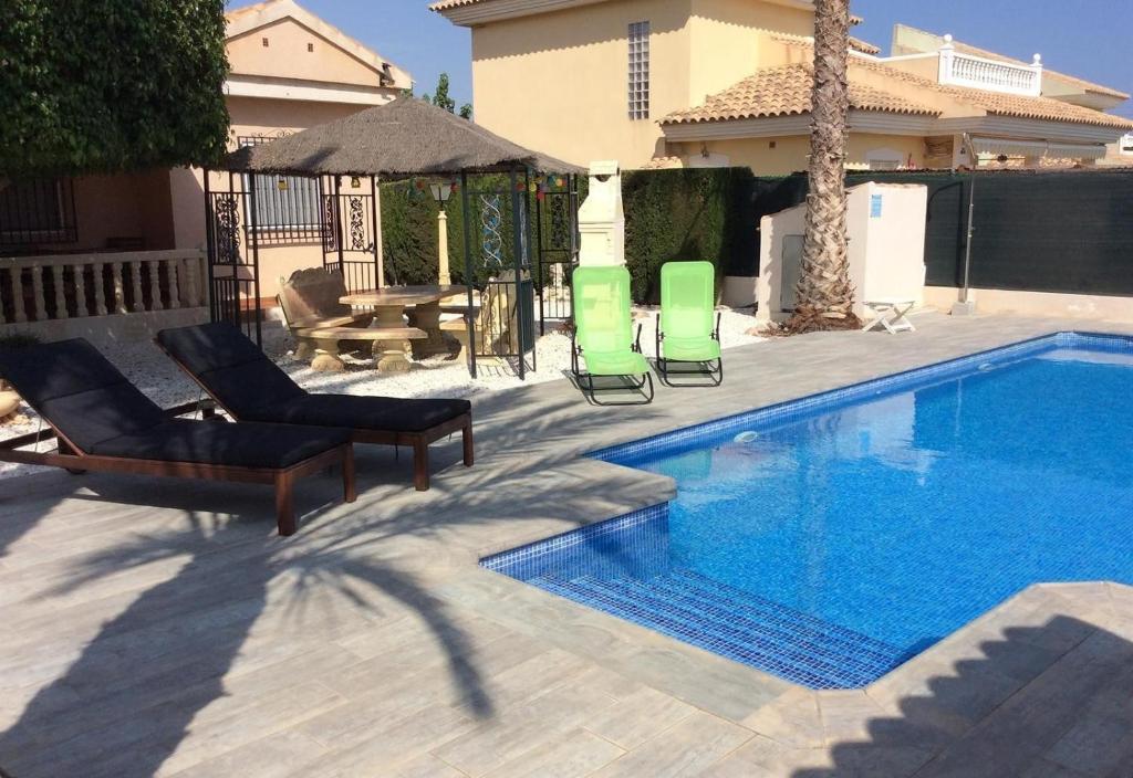 a swimming pool with two lawn chairs and a table at Casa Cuesta in Bolnuevo