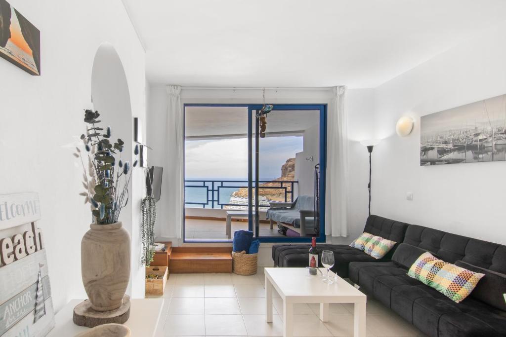 a living room with a black couch and a table at Stunning Sunset Ocean View Apt in Taurito