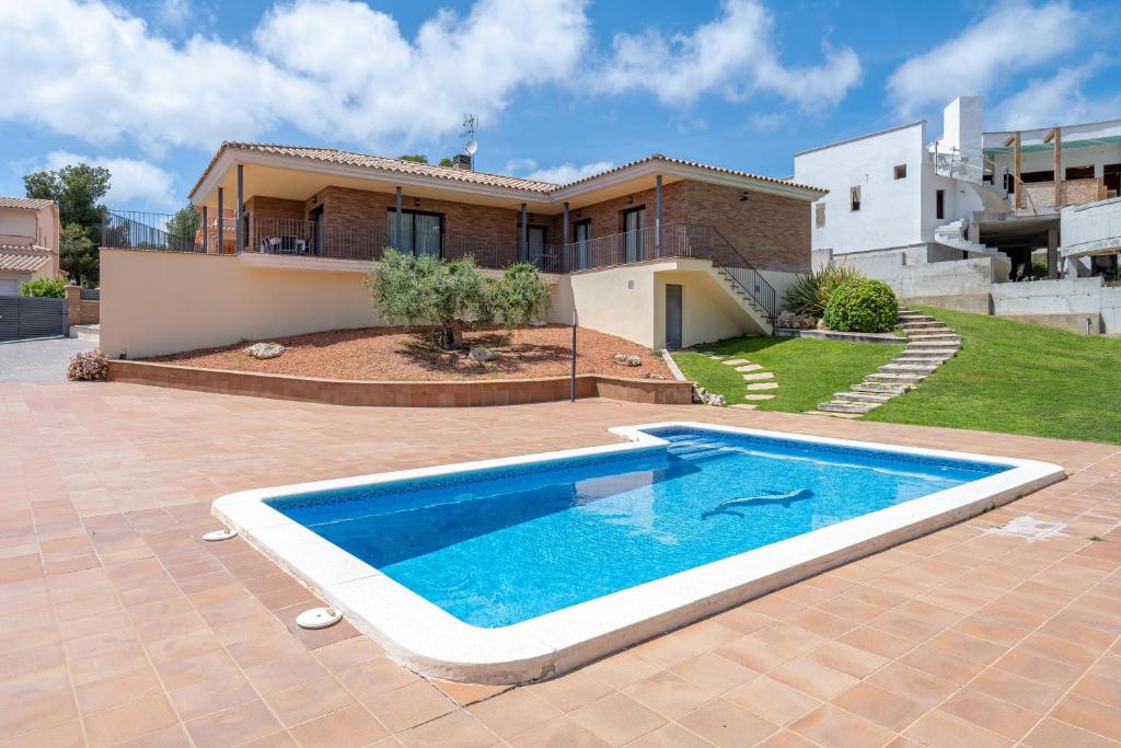 a villa with a swimming pool in front of a house at Casa Tico in Roda de Bará