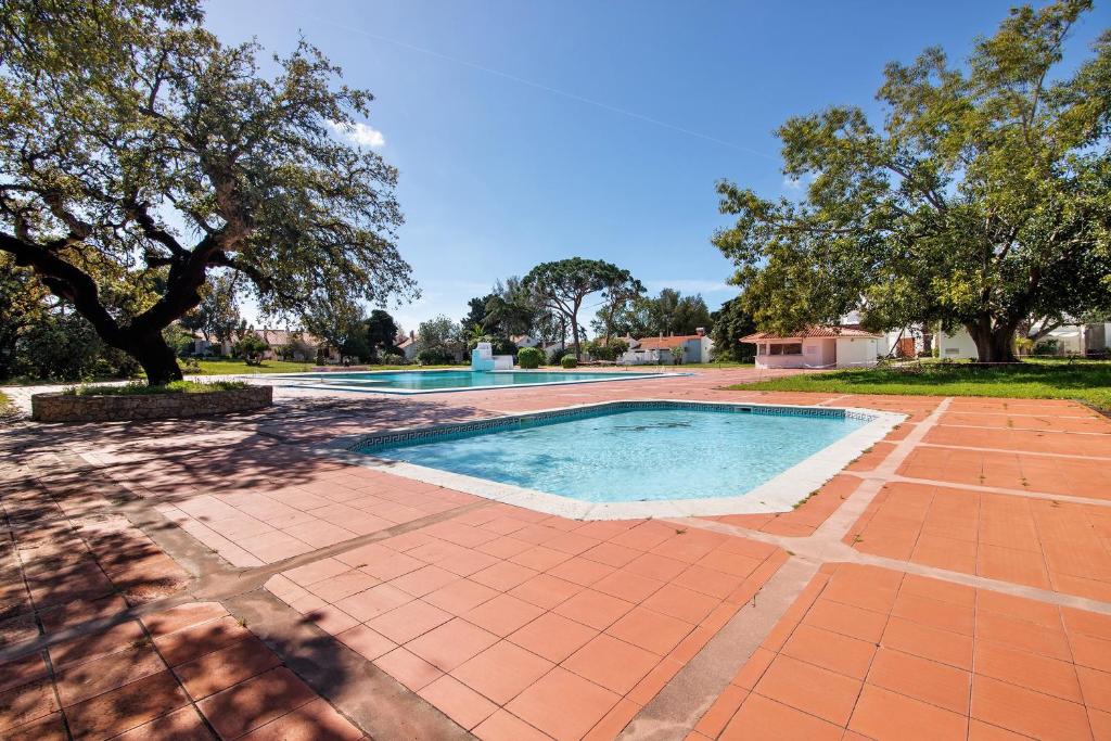 a swimming pool in a yard with trees at Amazing Oura Beach Apartment in Albufeira