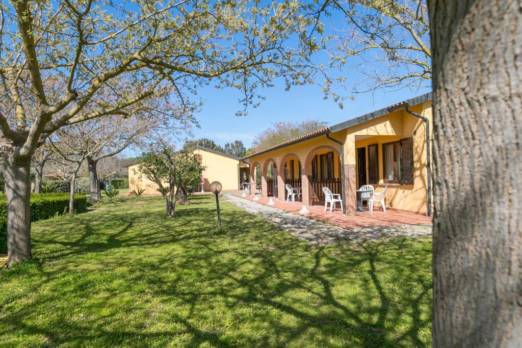 a yellow house with a yard with chairs on it at Il Girasole - Mirto in Venturina Terme