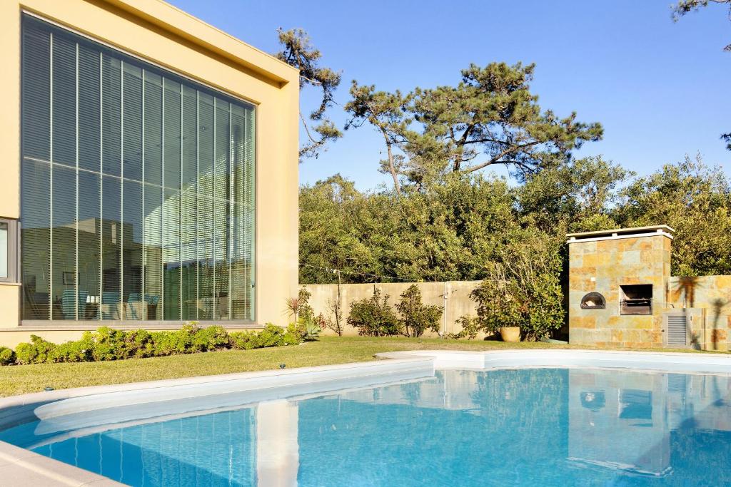 a swimming pool in front of a house at Casa dos Pinheiros in Apúlia
