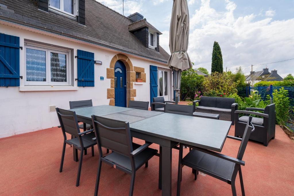 a patio with a table and chairs and a house at La Maison Bleue 3 étoiles in Plouhinec