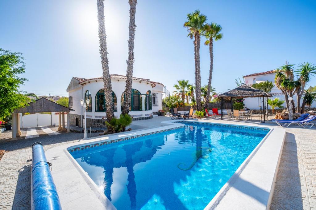 a swimming pool in front of a house with palm trees at Casa Nero in San Fulgencio