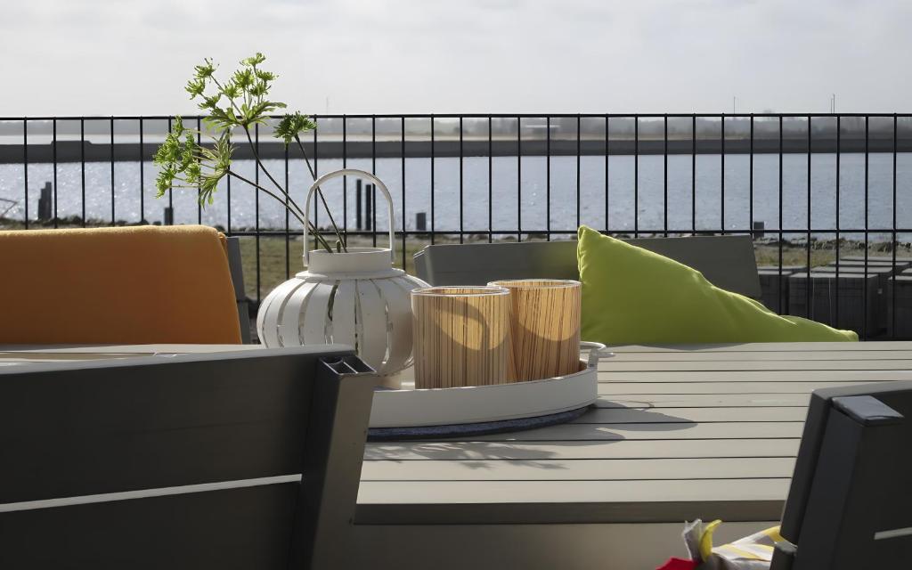 a table with a vase and two cups on a balcony at Ferienhaus Olpenitz und Strand in Kappeln