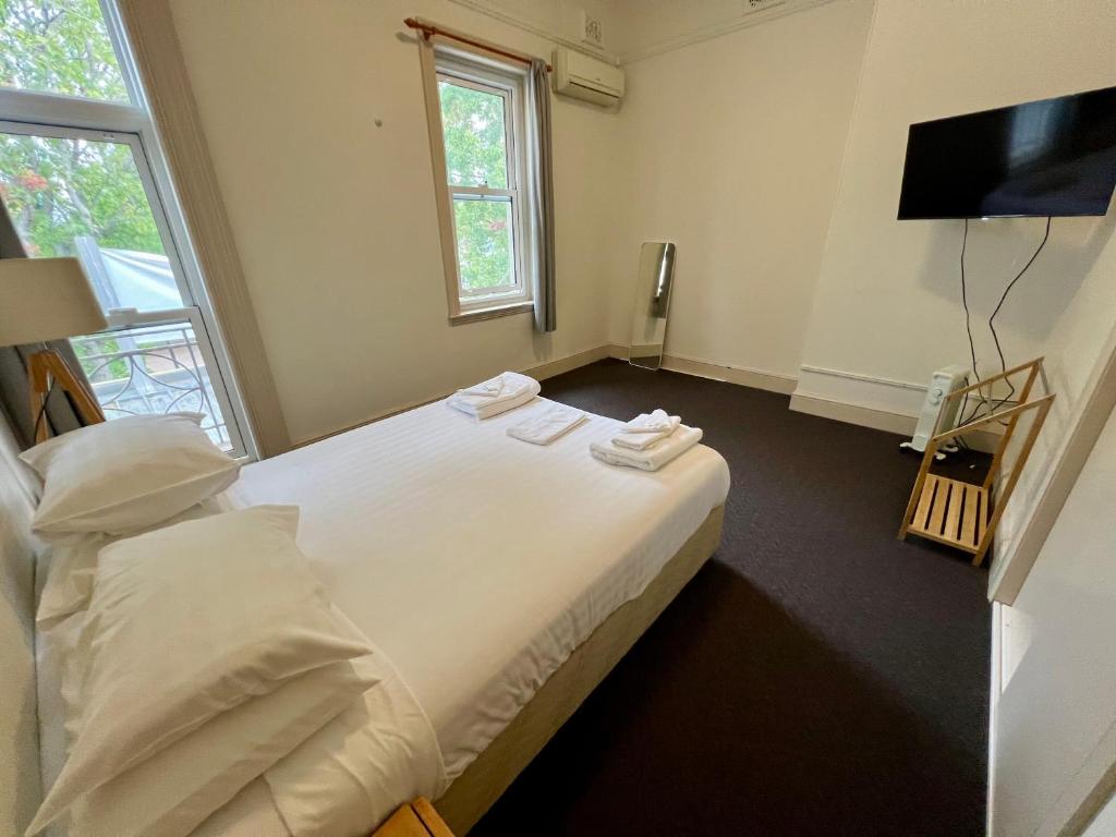 a bedroom with a large white bed and a television at Empire Hotel Goulburn in Goulburn