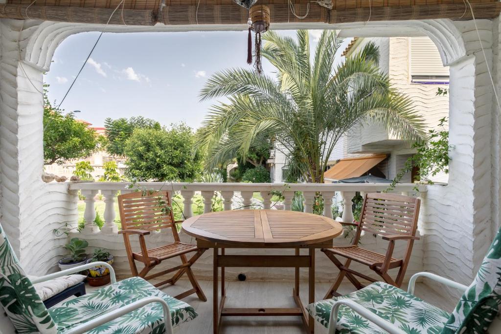a porch with a table and chairs and a palm tree at Casa en la playa con piscinas A in Puerto Marino