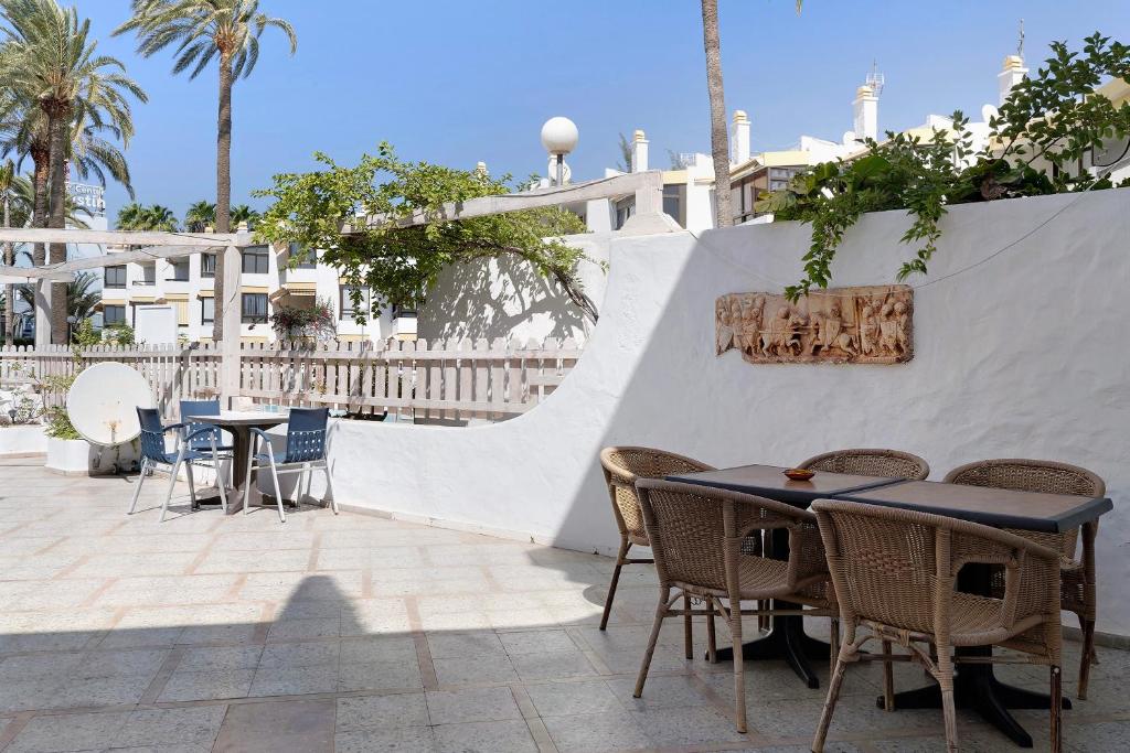 a patio with tables and chairs next to a white wall at Apartamento Las Flores4 in San Bartolomé