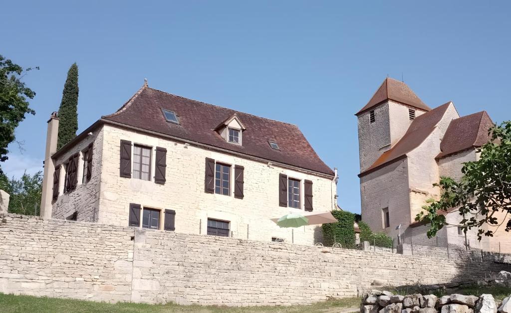 an old stone building with a tower behind a wall at La Maison Chez Karen in Séniergues