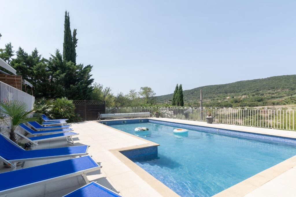 a swimming pool with blue lounge chairs next to it at Appartement N°2 - Piscine Partagée in Lagorce