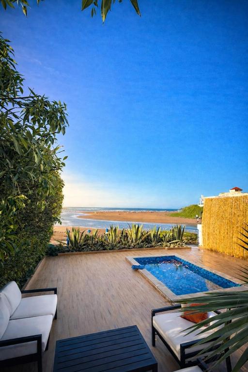 a patio with a pool and a view of the beach at Villa with pool and beach access in Ben Slimane