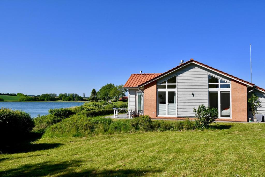 a house with a large lawn in front of a lake at Schwanenuferhaus in Kosel