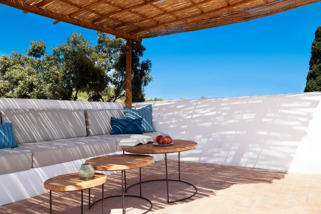 a patio with two tables and a couch at Casa Le Rocce San Pantaleo in San Pantaleo