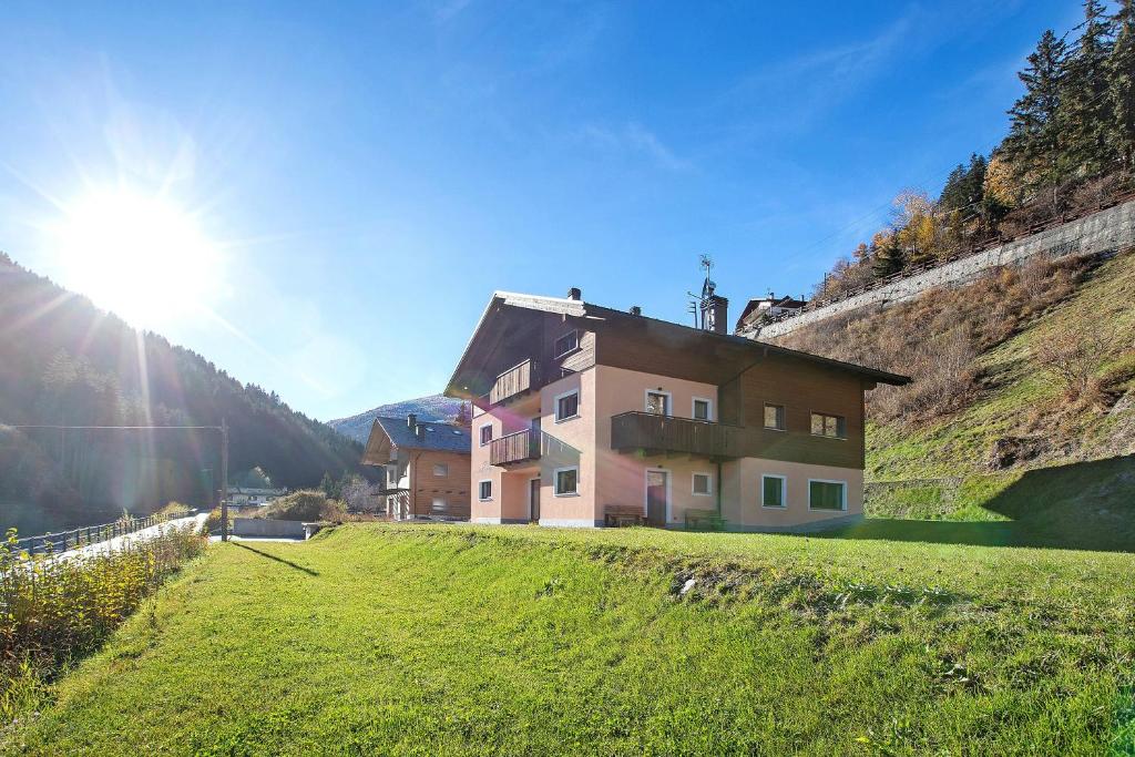 a house on a hill with the sun behind it at Chalet Serenella in Valdidentro