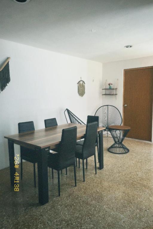a dining room with a wooden table and chairs at Casa Rouge Alojamiento Cerca de Uman in Mérida