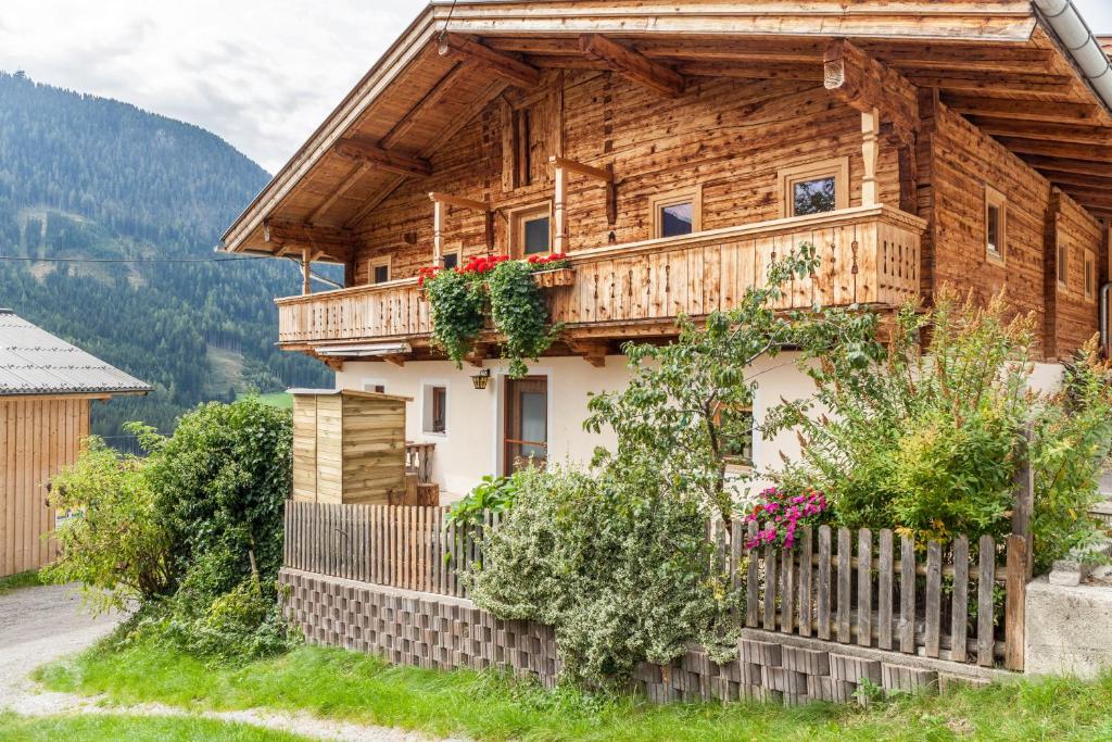 a wooden house with a balcony with flowers at Neuhaus Alm in Gerlosberg