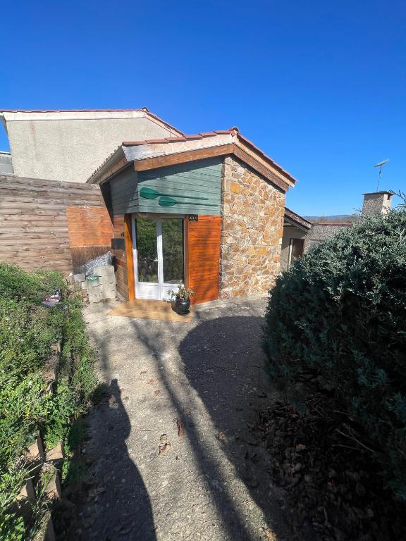 a stone house with a green roof and a driveway at Maison Donasete voyageurs in Vieille-Brioude
