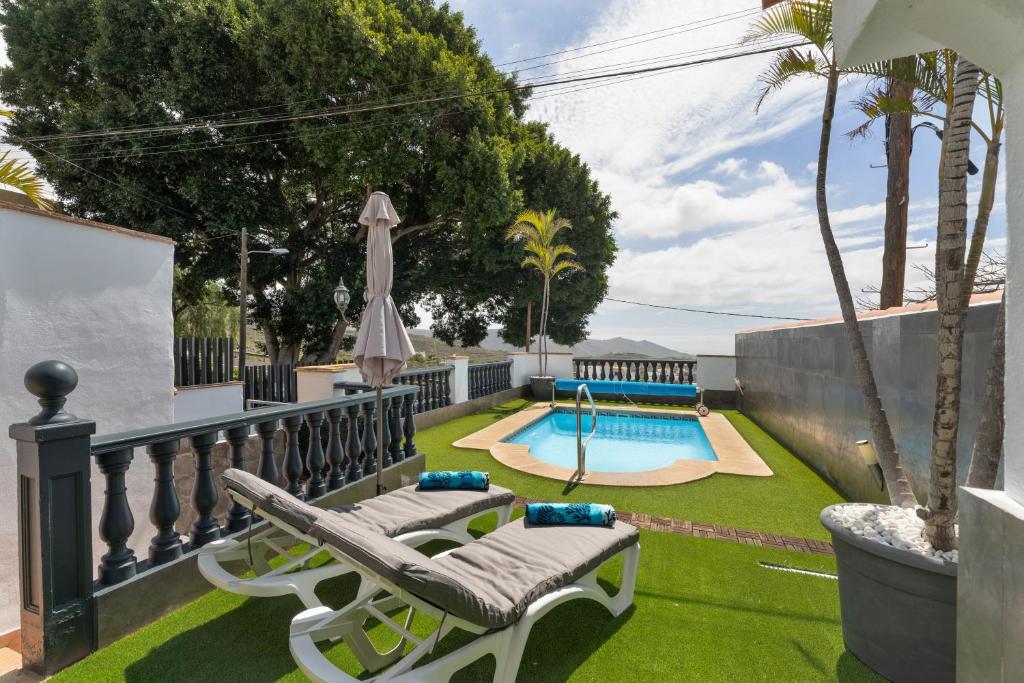 a backyard with a swimming pool and two lounge chairs at Casa Llano del Rey in Arona