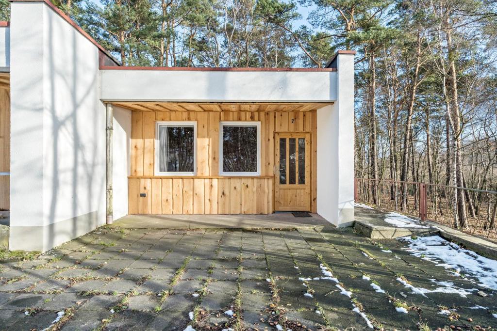 a home with a wooden garage with trees in the background at Bungalow 7 - Anglerinsel in Kollm