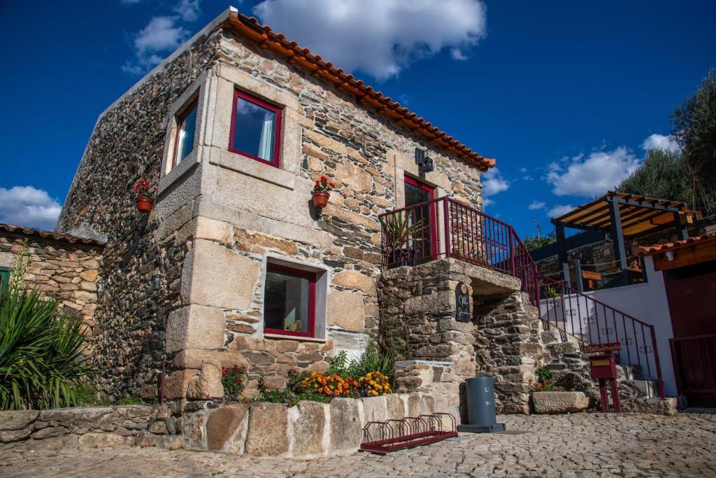 a stone house with red windows and a balcony at Villa Jerusalém - Casa de Campo in Romeu