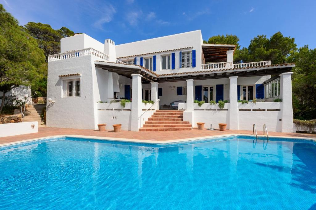 a white house with a swimming pool in front of it at Villa Renate in Sant Josep de sa Talaia