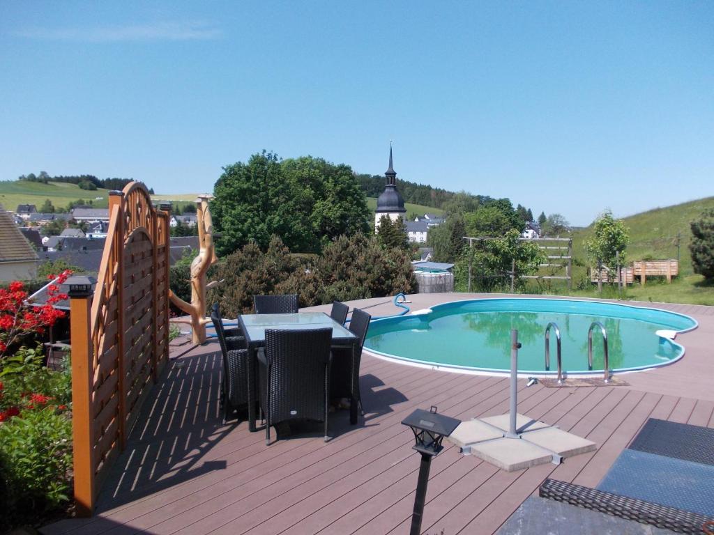 a swimming pool with a table and chairs on a deck at Ferienwohnung Neubert in Eibenstock