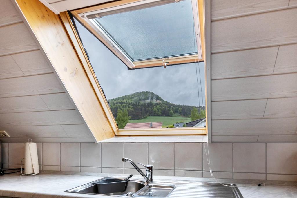 a kitchen sink and a window with a mountain view at Fewo unterm Dreifaltigkeitsberg in Balgheim