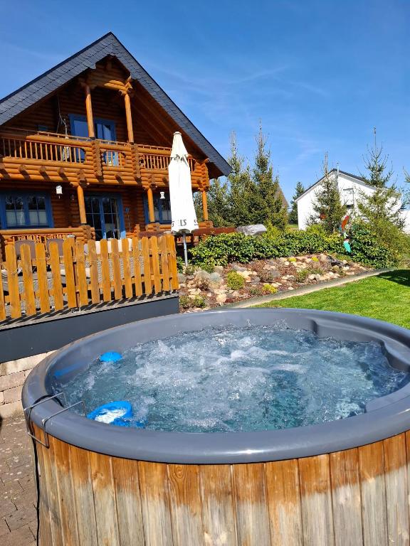 a hot tub in front of a log cabin at Holzhaus Mühlenblick mit Whirlpool in Medebach