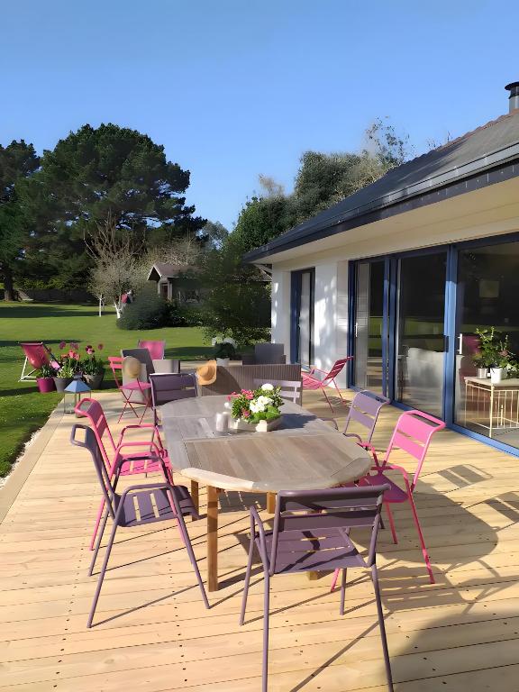 a patio with pink chairs and a wooden table at Chambres Er Vingle - Locmariaquer in Locmariaquer