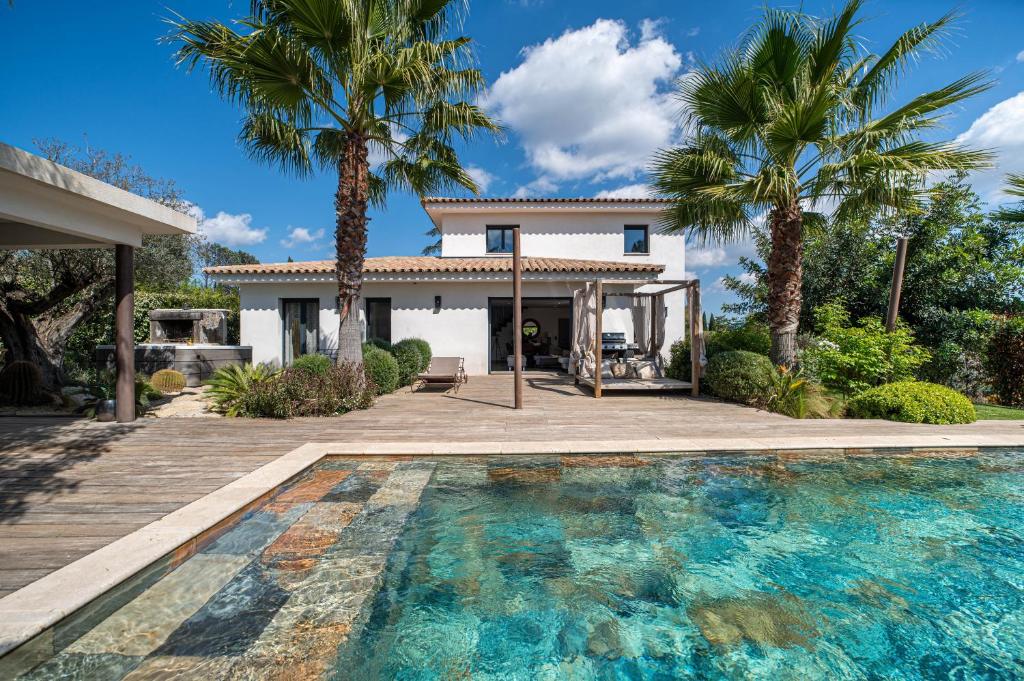 a house with a swimming pool and palm trees at Eden Balinais in Le Muy