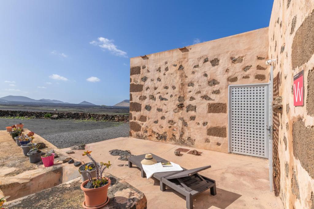a patio with a table and chairs next to a stone wall at Finca El Tablero in Tinajo