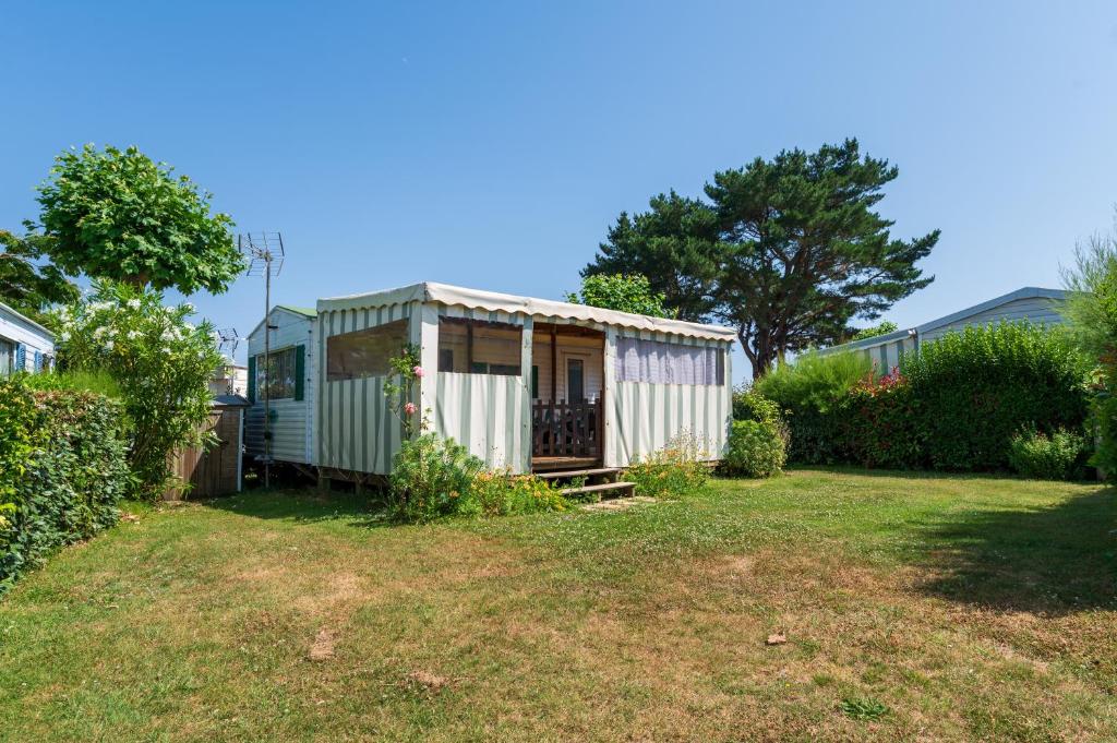a small white shed in a yard at Mobilhome kervoyal 56 in Damgan