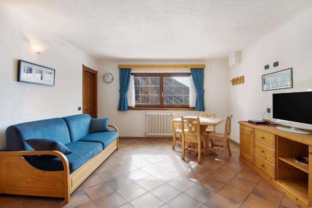 a living room with a blue couch and a table at Residence Larice Bianco App n5 in Campodolcino