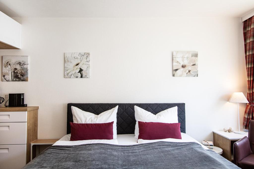 ein Schlafzimmer mit einem Bett mit roten und weißen Kissen in der Unterkunft Syltbrise 22 in Sylt