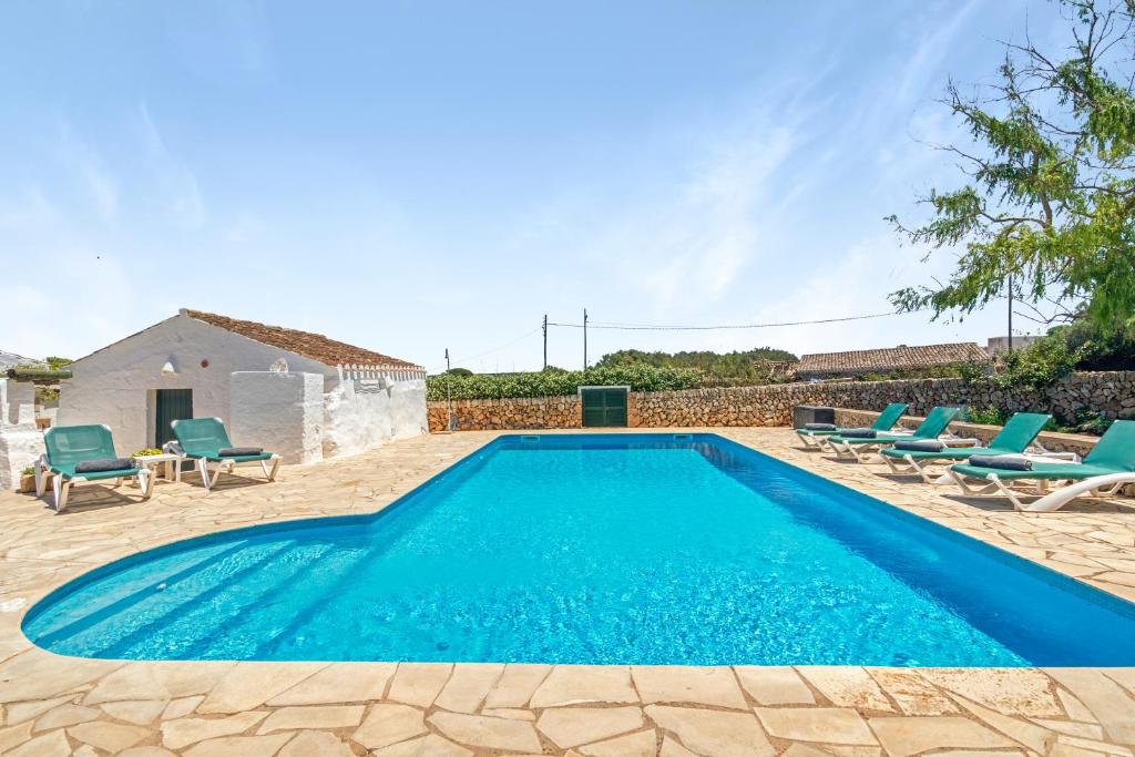 a swimming pool with chairs and a house at Finca Son Sanxo in Alaior