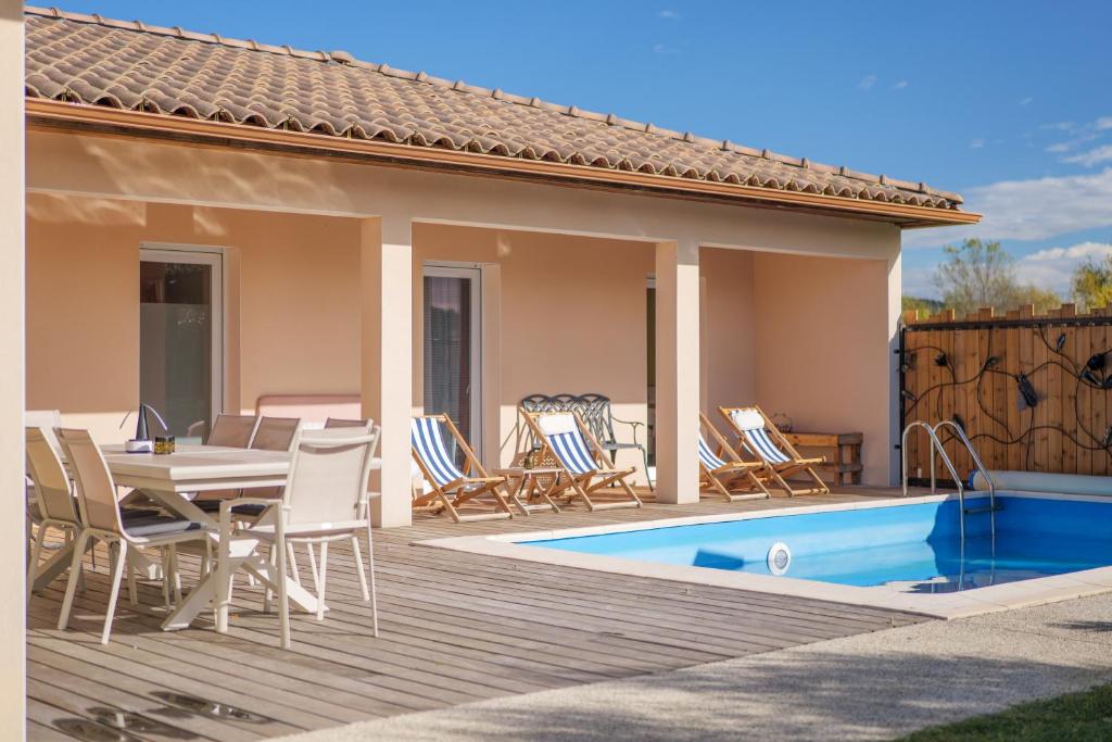 a patio with a table and chairs next to a pool at Villa M Vallon Pont d'arc in Vallon-Pont-dʼArc