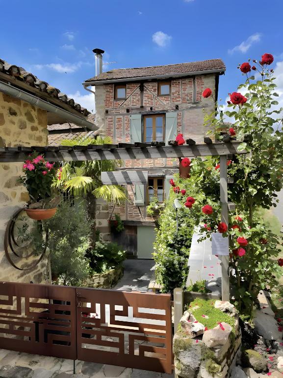 a house with flowers and a fence in front of it at Chambres D'hôtes du Pentadou in Felzins