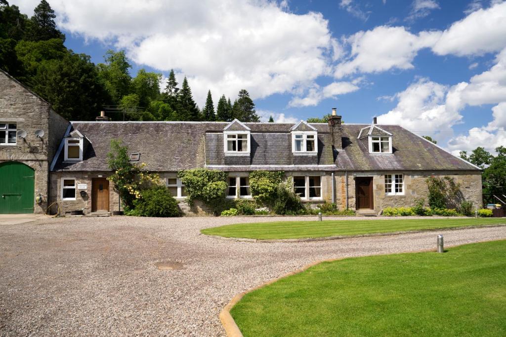 una casa con una puerta verde y una entrada de grava en Keepers Cottage, en Dunkeld