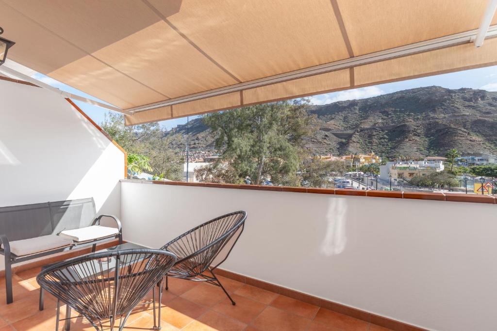 a balcony with chairs and a view of a mountain at Vv Caracola in Puerto de Mogán