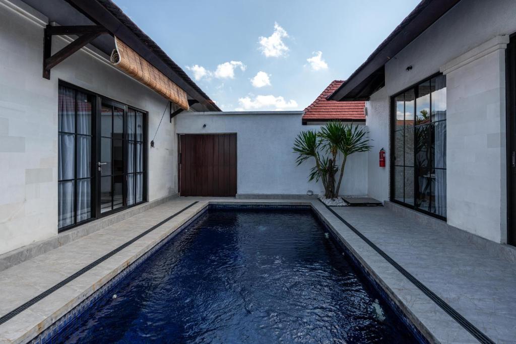 a house with a swimming pool in front of a house at Blue Marlin Villas Legian in Legian
