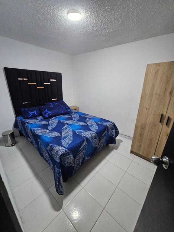 a bedroom with a bed with a blue comforter at Departamento central Lg in Pereira