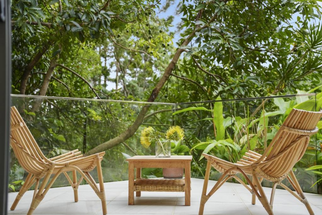 two chairs and a table on a porch with trees at Secluded rainforest getaway in Currumbin Valley