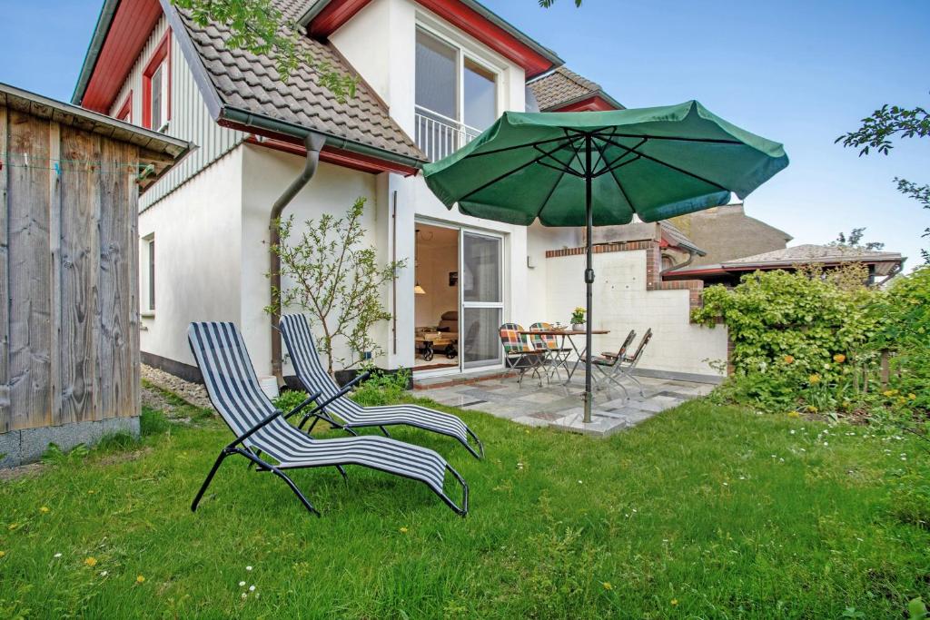 two chairs and an umbrella in the yard of a house at Haus Schilfblick in Wieck