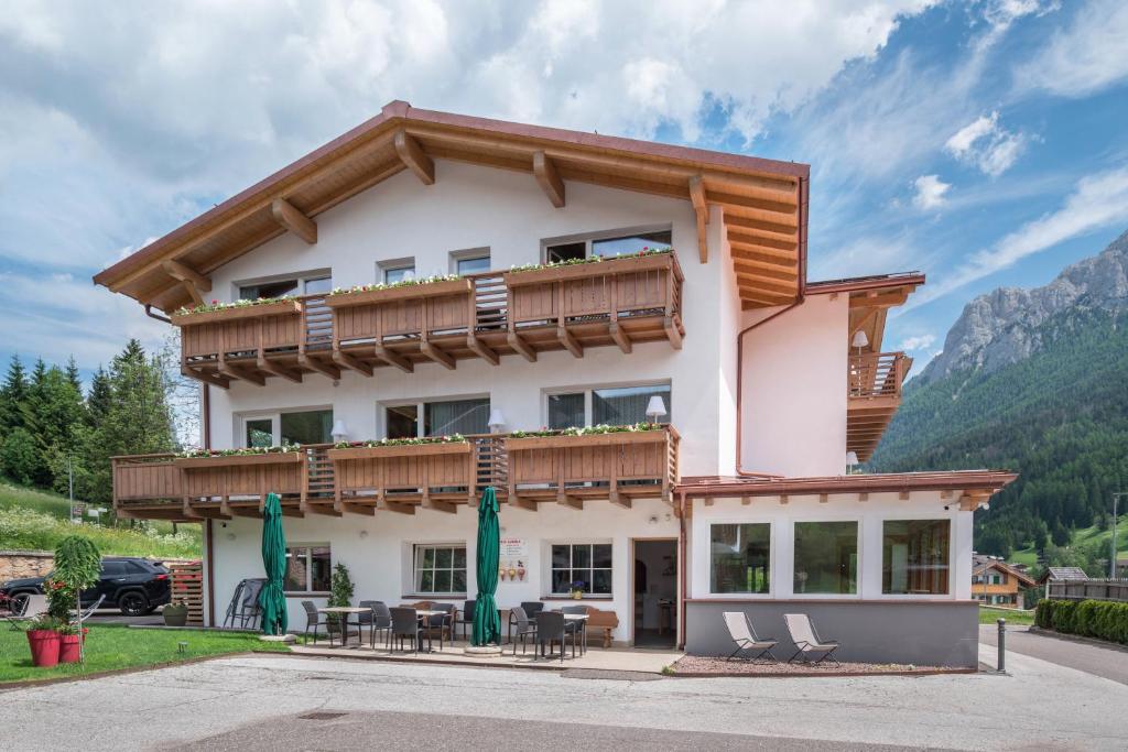 a house in the mountains with tables and chairs at Apart Wellness Alpino con minispa in Soraga