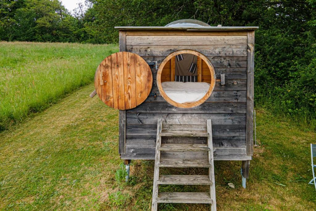 a wooden out house with a ladder and a window at Cabane aux étoiles in Auriac-du-Périgord