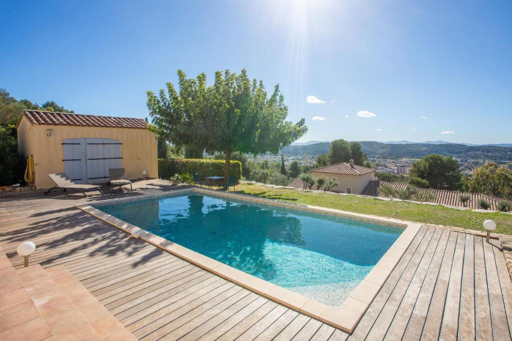 a swimming pool with a wooden deck next to a house at La Vue des Anges in Draguignan