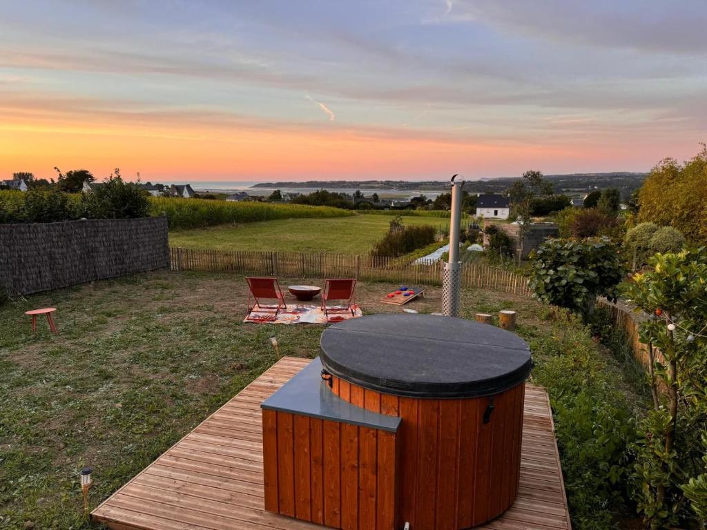 a wooden deck with a hot tub and a table at Tiny House 'bada' Vue Mer in Langueux