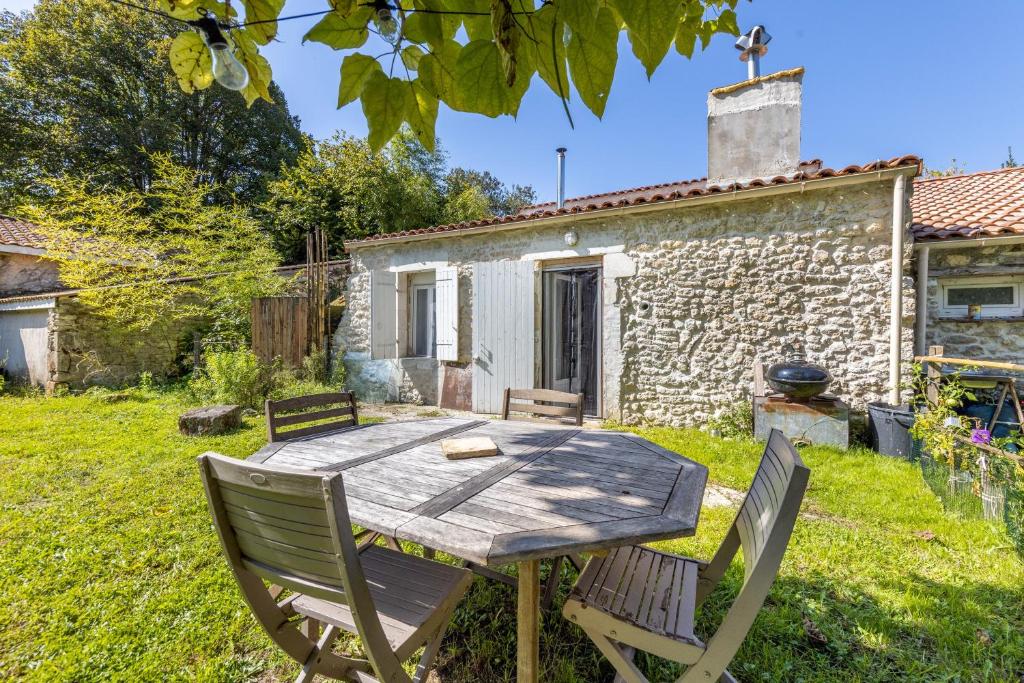 a wooden table and chairs in front of a cottage at Maison calme d'Amélie in Saint-Germain-dʼEsteuil