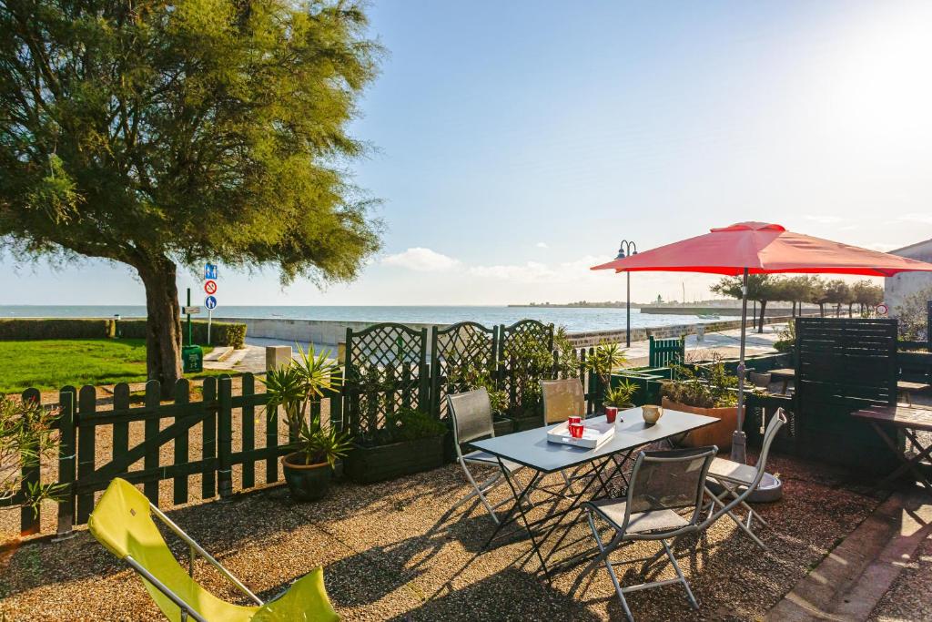 a patio with a table and chairs and an umbrella at Maison de la côte in La Flotte